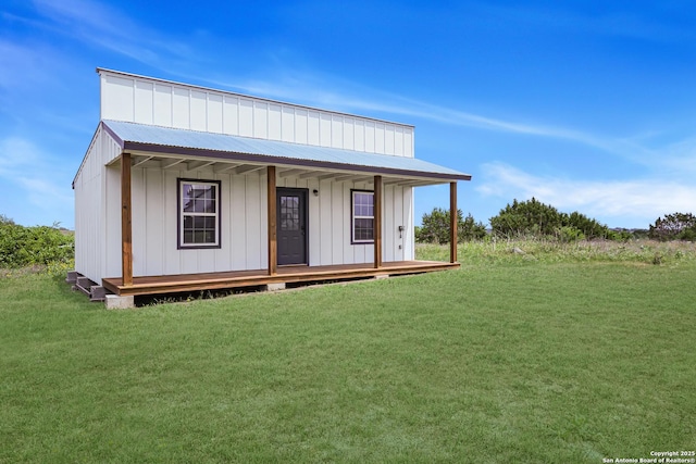 view of front facade with metal roof, covered porch, board and batten siding, and a front yard