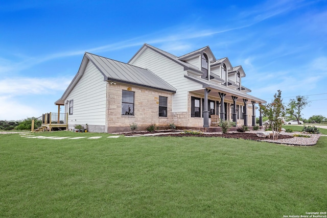 view of front of property featuring a standing seam roof, a porch, a front yard, stone siding, and metal roof