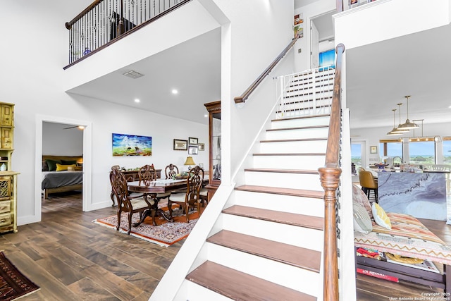 stairway with visible vents, baseboards, a towering ceiling, and parquet floors