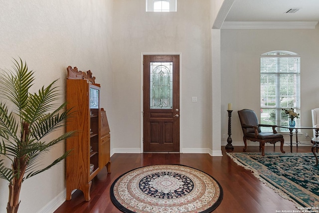 entrance foyer with arched walkways, wood finished floors, baseboards, and ornamental molding