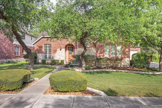 view of front of home featuring brick siding, stone siding, and a front yard