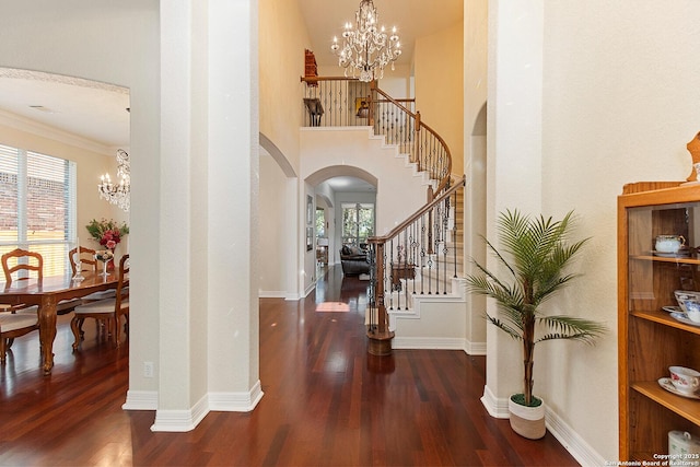 foyer entrance with arched walkways, plenty of natural light, an inviting chandelier, wood finished floors, and stairs