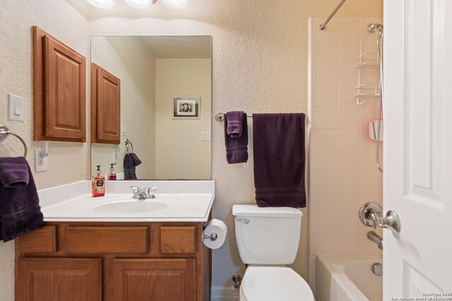 bathroom with toilet, a textured wall, and vanity