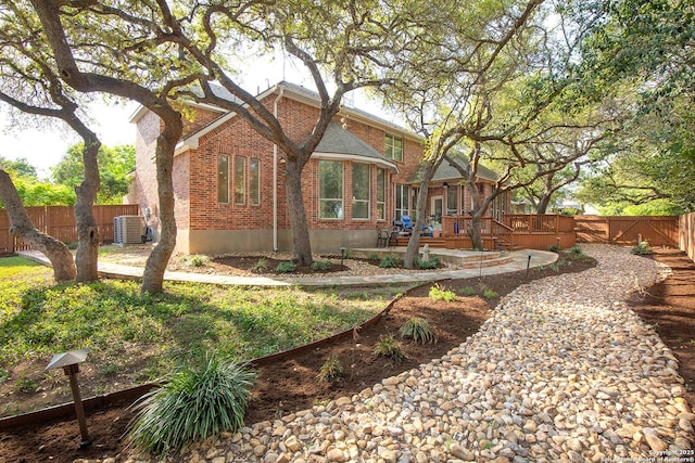 rear view of house with fence, brick siding, cooling unit, and a patio