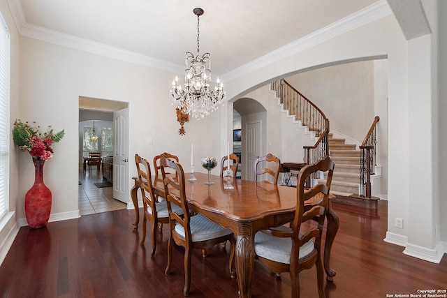 dining room with stairway, crown molding, wood finished floors, arched walkways, and baseboards