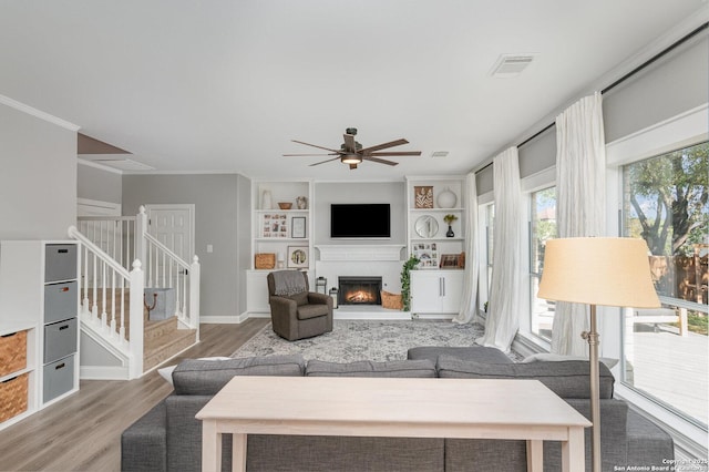 21707 Beaver Bnd, San Antonio, TX 78258 - living room with wood finished floors, stairs, a glass covered fireplace, ceiling fan, and visible vents