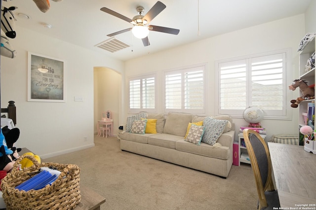 carpeted living room with arched walkways, a ceiling fan, visible vents, and baseboards