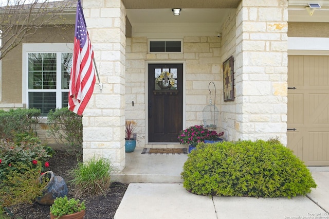 doorway to property with stone siding and a garage