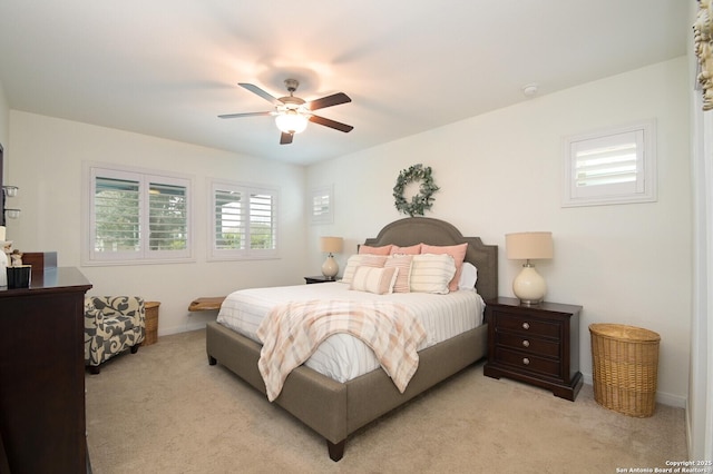 bedroom with light colored carpet, ceiling fan, and baseboards