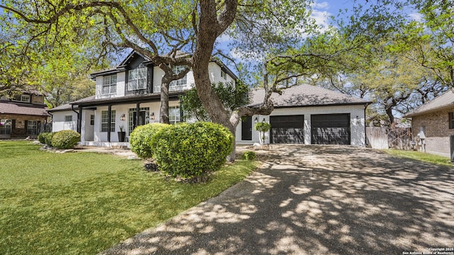 traditional-style home with driveway, fence, brick siding, an attached garage, and a front yard