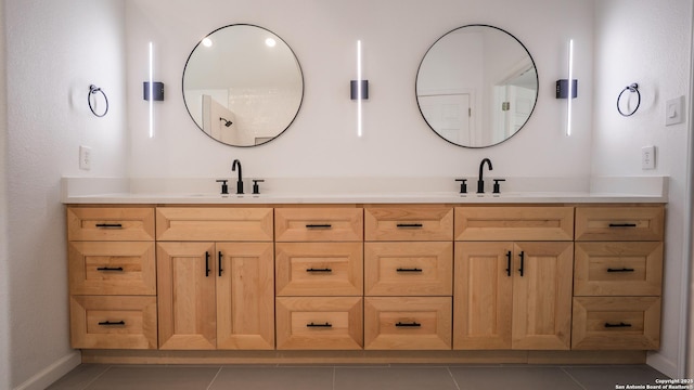 full bath with double vanity, tile patterned floors, baseboards, and a sink