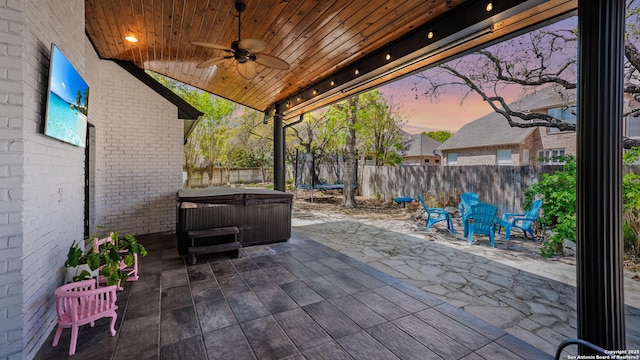 view of patio / terrace with ceiling fan, a fenced backyard, and a hot tub