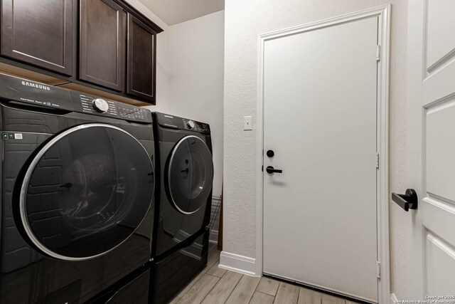 laundry room with light wood-type flooring, baseboards, washer and dryer, and cabinet space