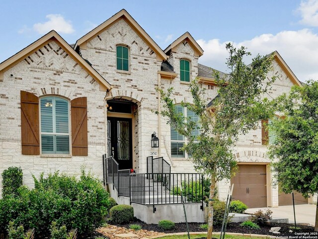 24742 Para Siempre, San Antonio, TX 78261 - view of front of house featuring an attached garage, brick siding, stone siding, and concrete driveway
