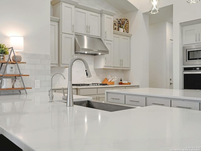 24742 Para Siempre, San Antonio, TX 78261 - kitchen with decorative backsplash, appliances with stainless steel finishes, under cabinet range hood, and light countertops