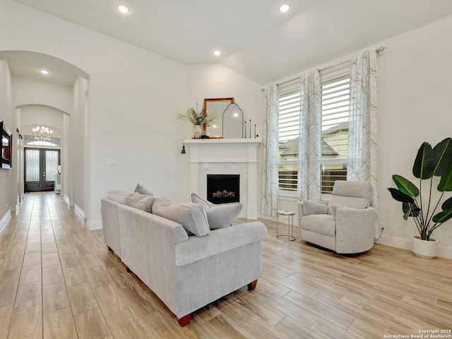 24742 Para Siempre, San Antonio, TX 78261 - living area featuring arched walkways, light wood finished floors, vaulted ceiling, and a fireplace