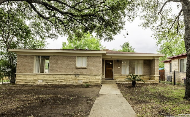 view of front of property featuring central AC, covered porch, fence, brick siding, and crawl space