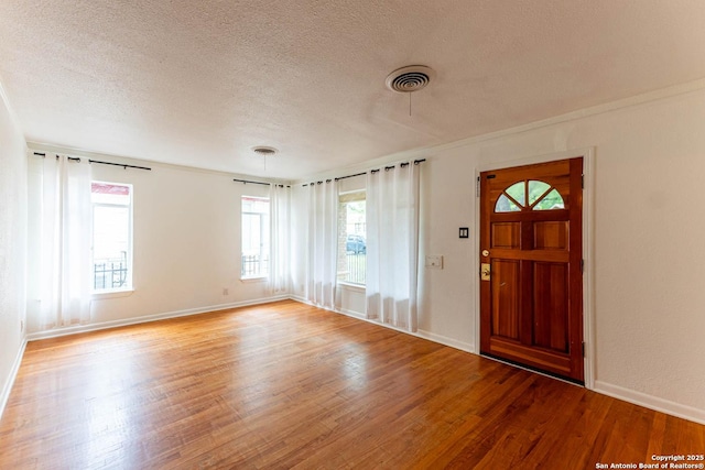 foyer with wood finished floors, a textured ceiling, baseboards, and visible vents