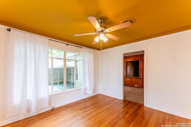 empty room featuring wood finished floors, baseboards, and ceiling fan