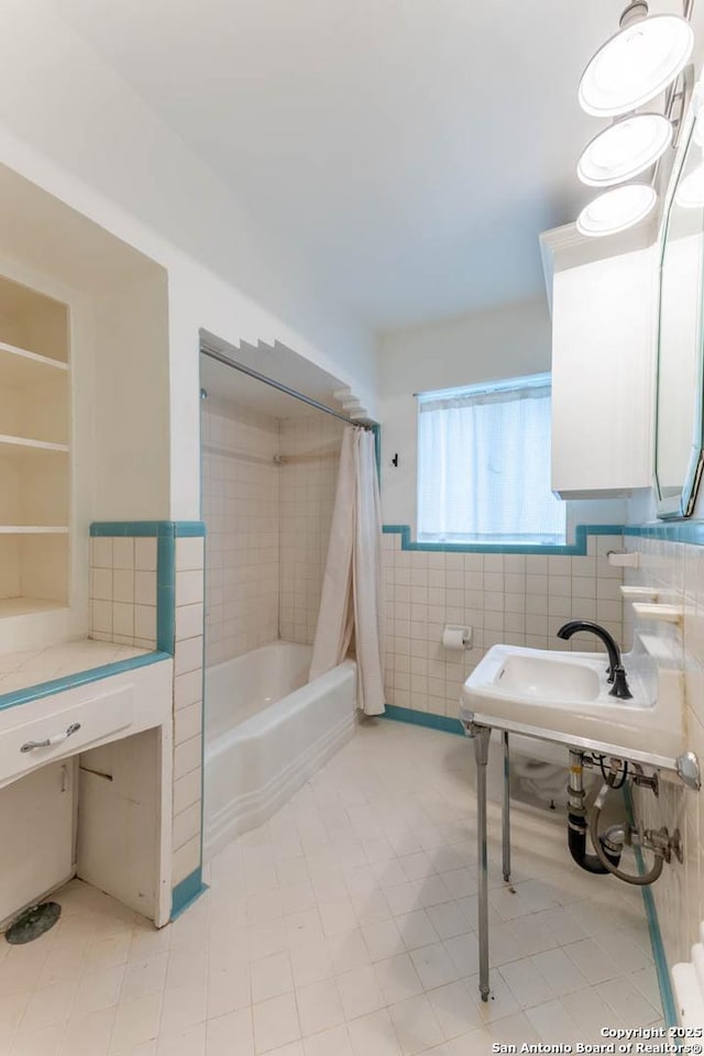 bathroom with tile patterned floors, shower / bath combo, a sink, tile walls, and wainscoting