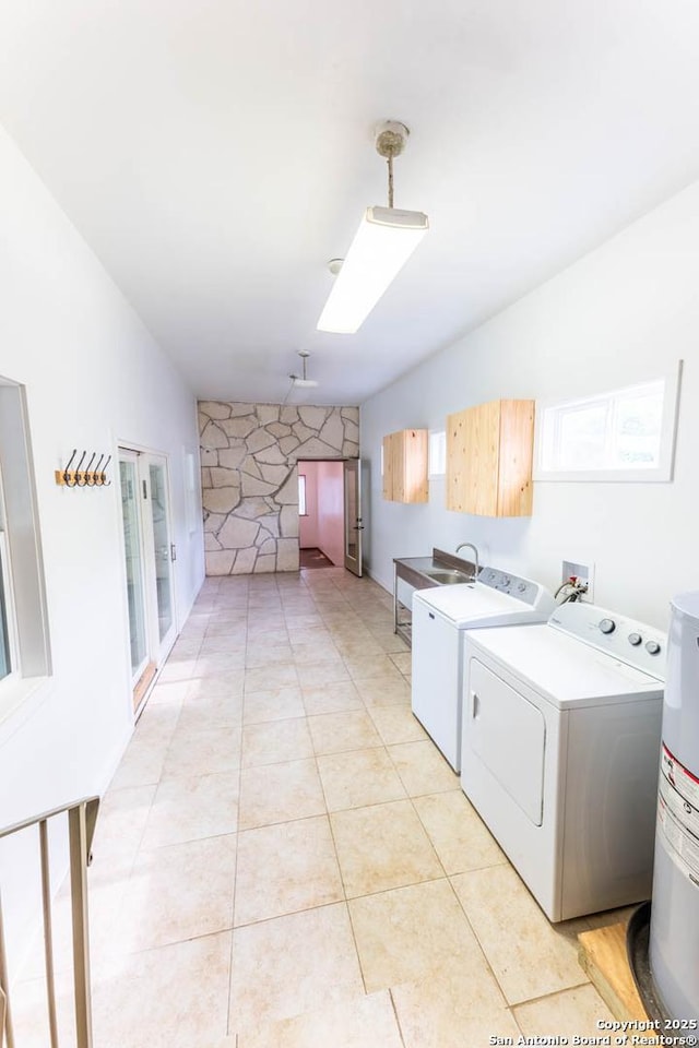 laundry area with a sink, a skylight, water heater, cabinet space, and washing machine and dryer
