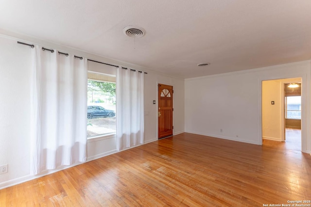 unfurnished living room featuring baseboards, light wood-style flooring, visible vents, and crown molding