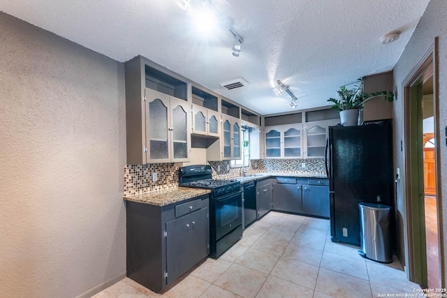 kitchen featuring tasteful backsplash, a textured wall, a sink, and black appliances