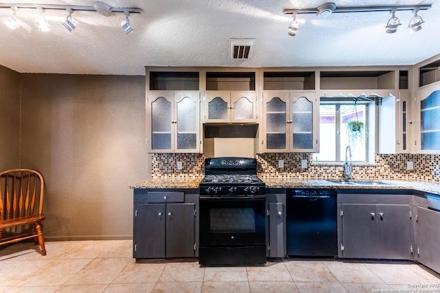 kitchen featuring track lighting, black appliances, decorative backsplash, and a sink