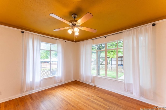 spare room featuring light wood-type flooring, baseboards, and ceiling fan