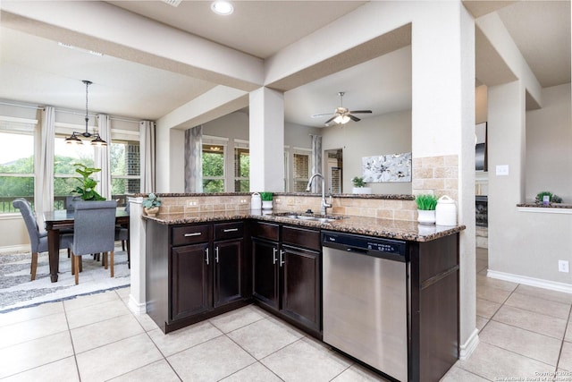 kitchen with stainless steel dishwasher, a sink, backsplash, light stone counters, and light tile patterned floors