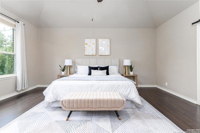 bedroom with vaulted ceiling, baseboards, and dark wood-type flooring