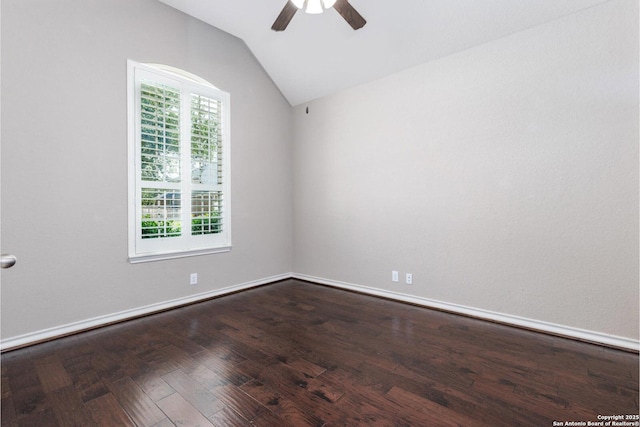 empty room featuring lofted ceiling, dark wood-style flooring, baseboards, and ceiling fan