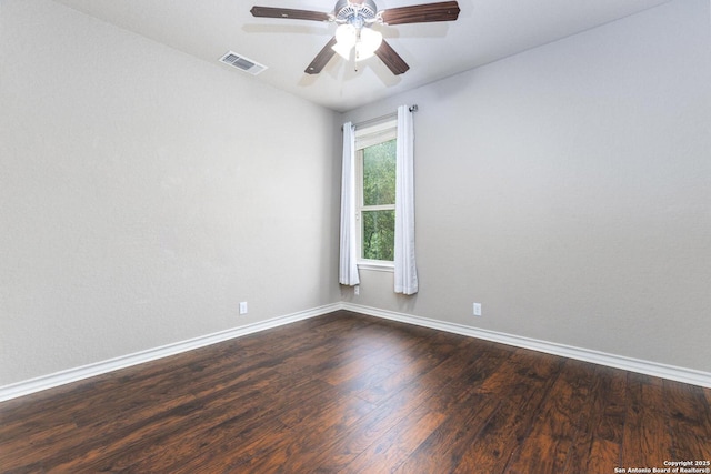 spare room featuring baseboards, a ceiling fan, visible vents, and dark wood-style floors