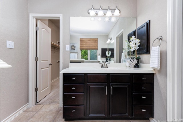 bathroom with baseboards, a textured wall, vanity, and tile patterned flooring