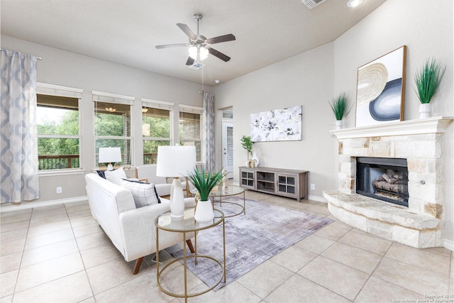 tiled living area featuring a fireplace, visible vents, baseboards, and ceiling fan
