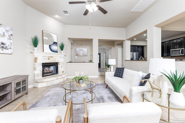 living area featuring a ceiling fan, visible vents, arched walkways, and light tile patterned flooring