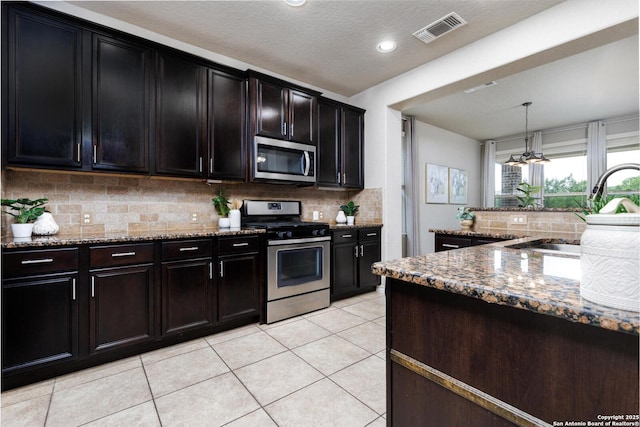 kitchen with stone counters, visible vents, decorative backsplash, and stainless steel appliances