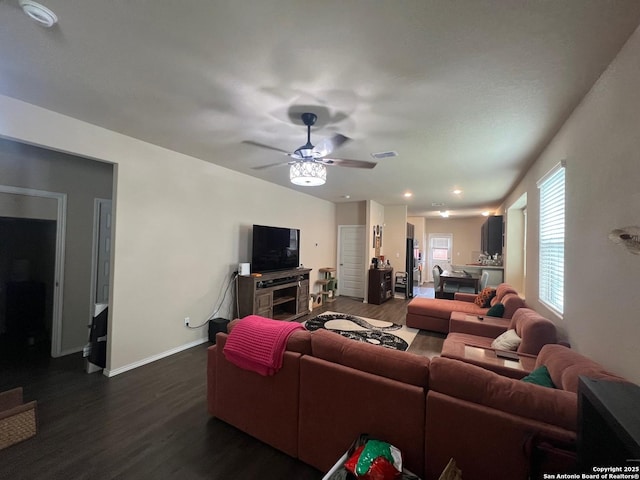 living room featuring visible vents, a ceiling fan, baseboards, and dark wood-style flooring
