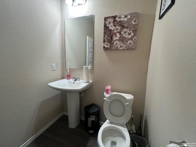 half bathroom with wood finished floors, toilet, and a sink