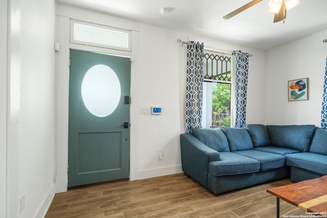 living area featuring wood finished floors, baseboards, and ceiling fan