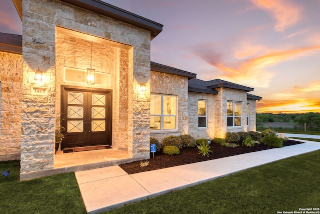doorway to property with a yard and stone siding