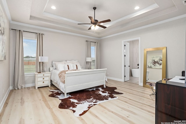 bedroom featuring baseboards, ornamental molding, light wood finished floors, and a raised ceiling