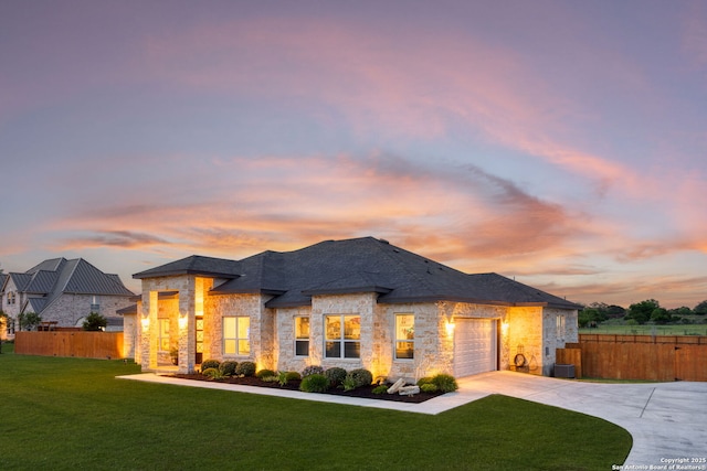 view of front of house featuring driveway, stone siding, a front lawn, and fence
