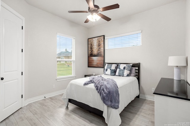 bedroom with light wood-style flooring, a ceiling fan, and baseboards