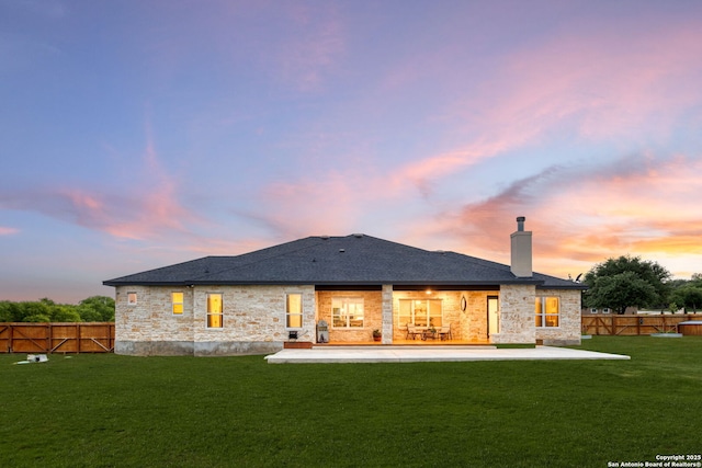 rear view of property with a chimney, a shingled roof, a fenced backyard, a yard, and a patio