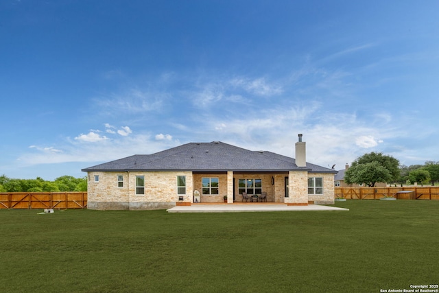 rear view of property with a yard, a patio area, a fenced backyard, and a chimney