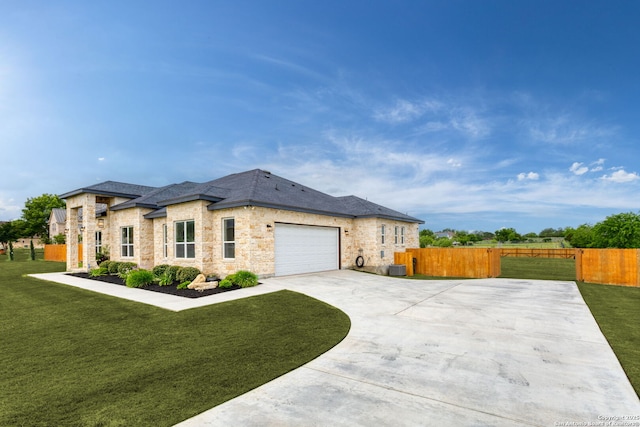 view of front of property featuring concrete driveway, a front lawn, stone siding, an attached garage, and fence