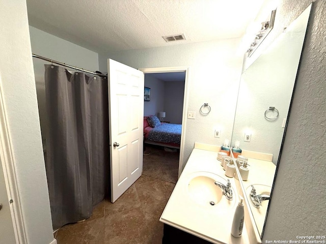bathroom with a textured ceiling, a textured wall, visible vents, and vanity