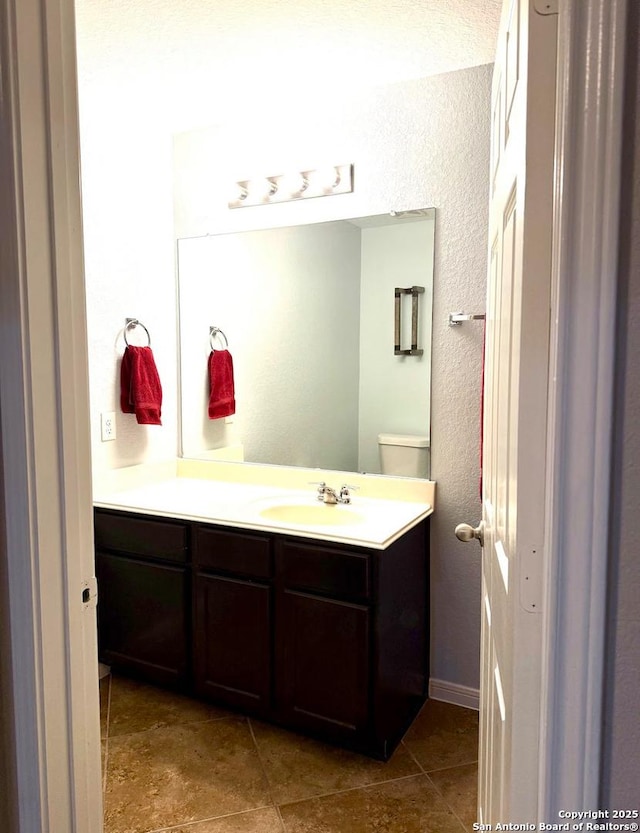 bathroom with a textured wall and vanity