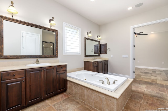 bathroom with two vanities, a jetted tub, a ceiling fan, and a sink